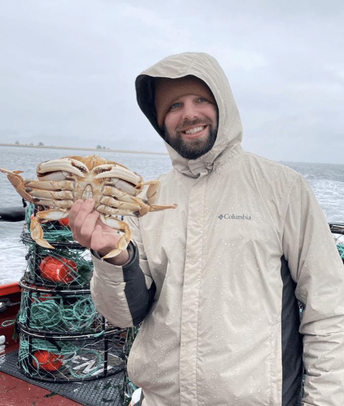 Zack holding a freshly caught Dungeness crab on a boat