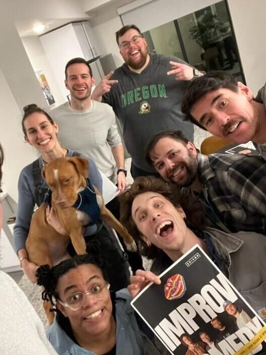 Zack's improv comedy troupe posing with a show poster